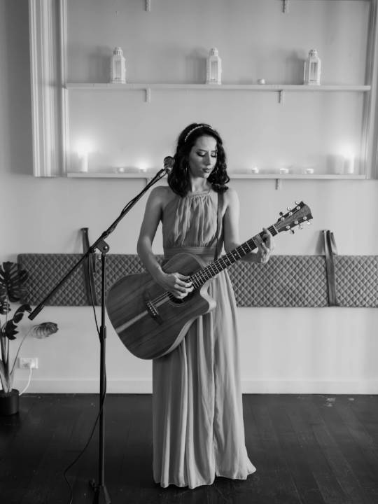 Bella Maree Music black and white image of girl singing and playing guitar in long dress