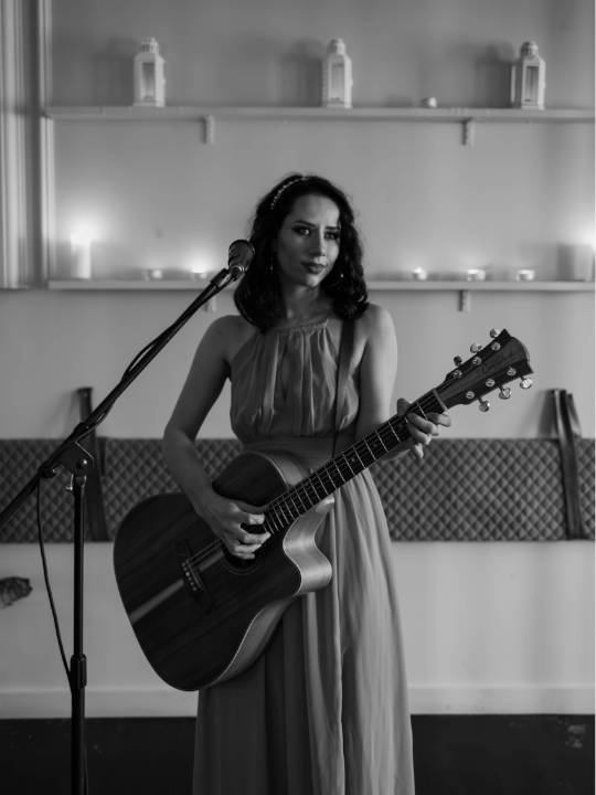 Bella Maree Music black and white image of girl singing and playing guitar in long dress